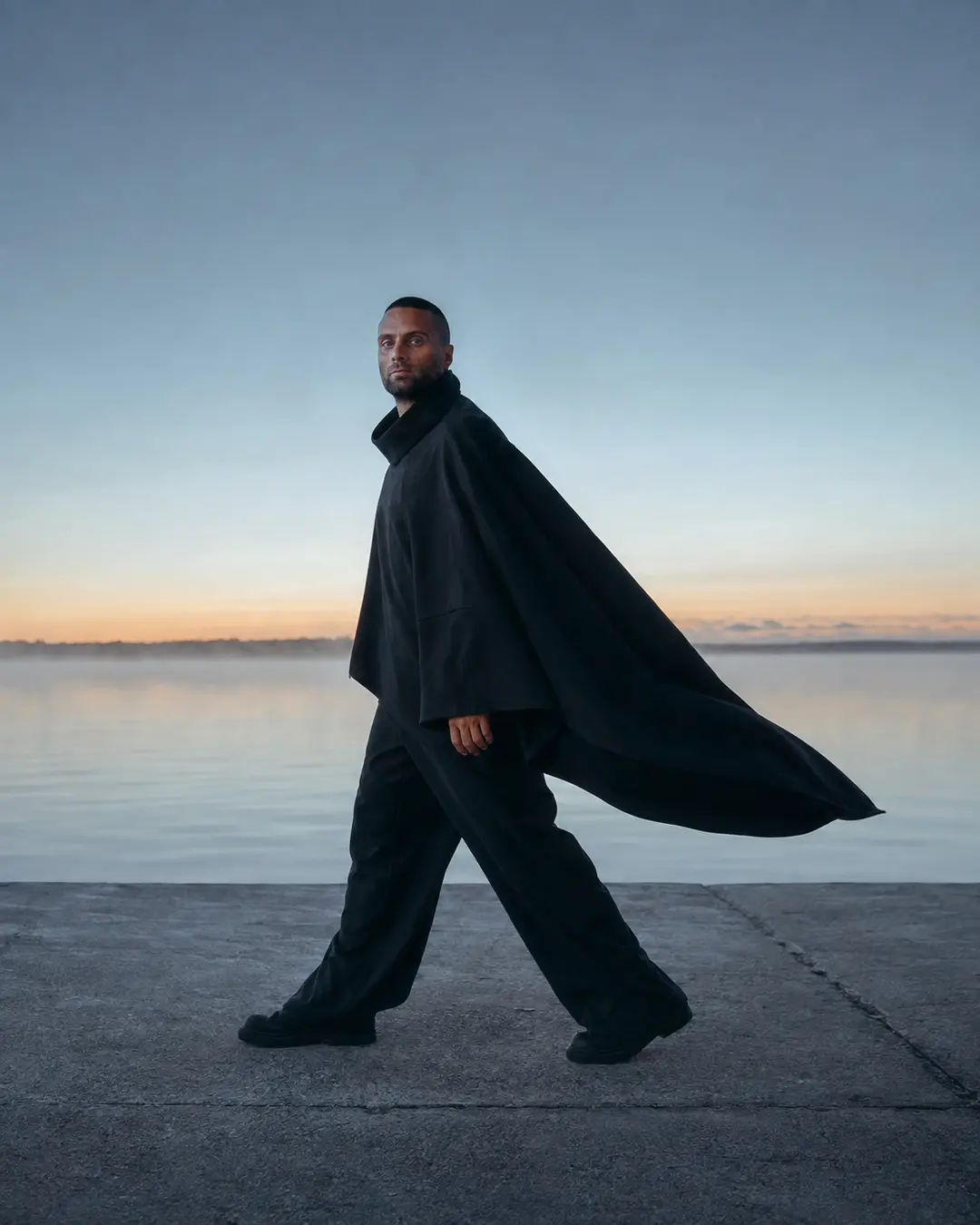 Text-free blue-dawn coastal portrait of Paul Lizzi in an oversized black architectural silhouette
